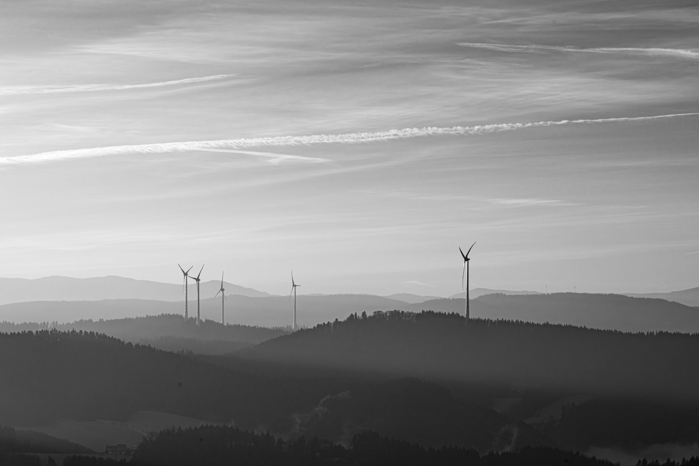 Éoliennes dans la brume d'un petit matin, dressées dans un ciel immense